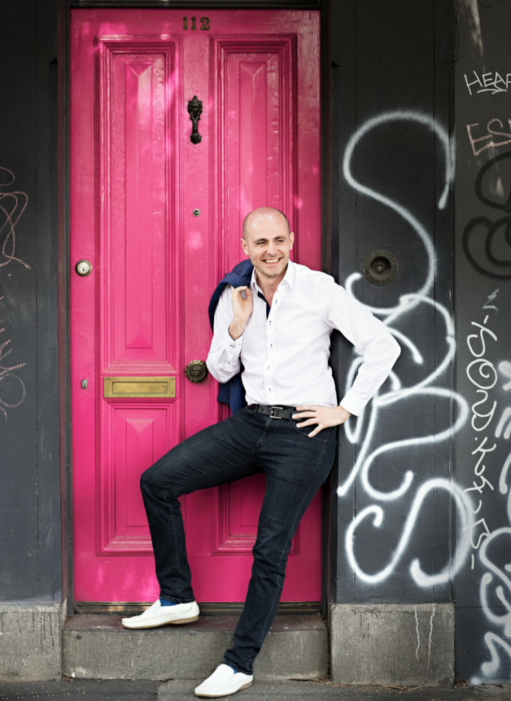 Nicholas Tamagna, countertenor and web designer, in front of pink door in Melbourne, Australia.